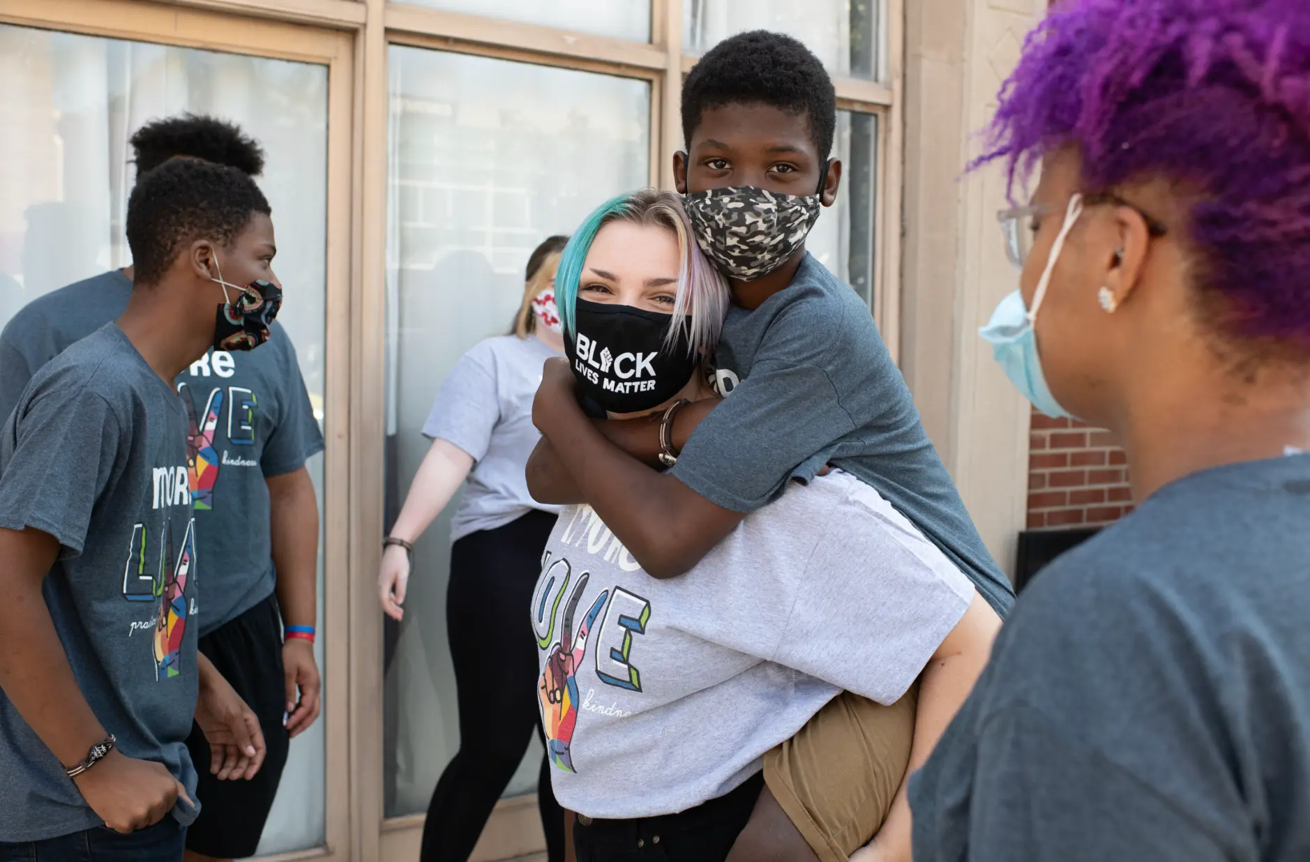 Program staff member carrying a smiling youth